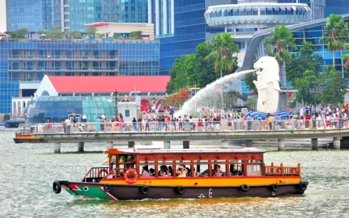 Traditional wooden bumboat sailing past the iconic Marina Bay Sands