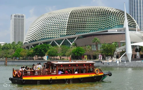 Tourists enjoying the outdoor deck of a Singapore River boat tour at sunset