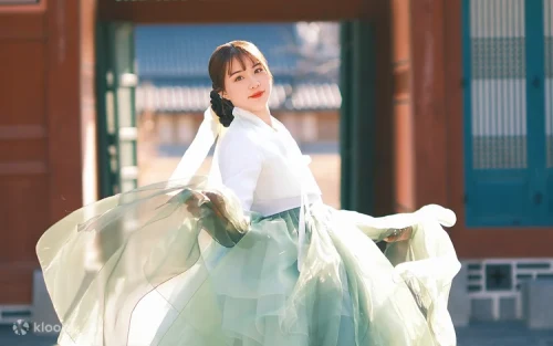 Couple wearing elegant Hanbok outfits walking through Gyeongbokgung Palace courtyard.