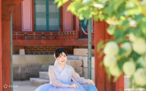 Group of friends taking photos in colorful themed Hanboks against historic palace walls.