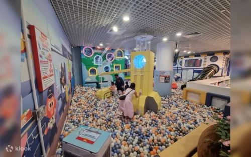 Kids sliding down the colossal funnel slide into the massive ocean ball pit at Jewel Changi.