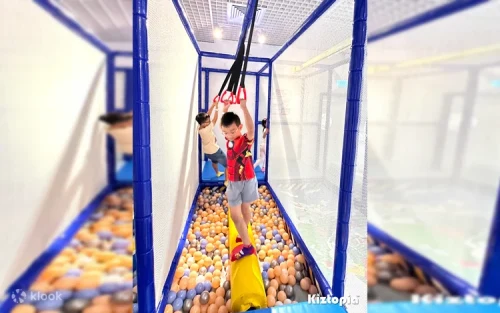 Children playing the interactive ball-shooting game wall at the indoor park.