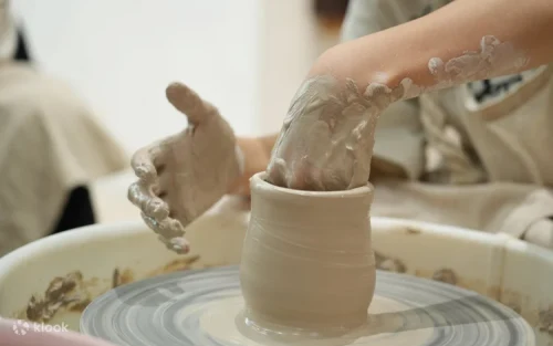 Instructor guiding a student in creating ceramic art in Singapore