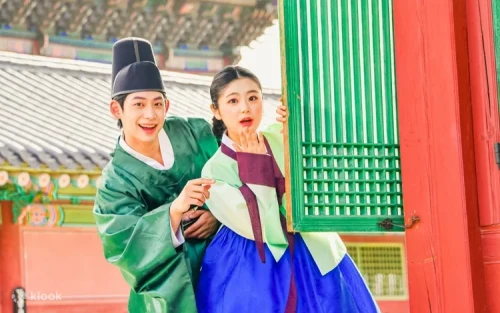 Couple wearing royal Hanbok costumes strolling through Gyeongbokgung Palace grounds