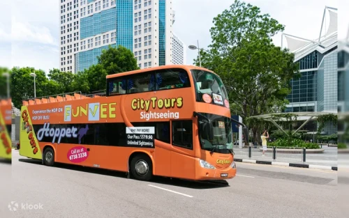 Open-top double-decker bus driving past the iconic Merlion Park
