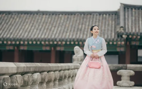 Couple walking through Gyeongbokgung Palace courtyards in vibrant Korean traditional attire.