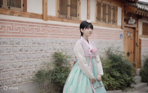 Friends taking photos in front of historic Bukchon Hanok Village wearing pastel hanboks.