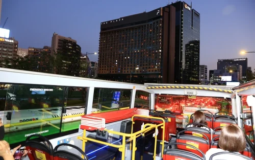 Open-top double-decker bus driving through illuminated Seoul streets