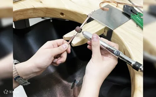 Participant using a specialized hammer to shape a metal bangle on a jeweler's anvil