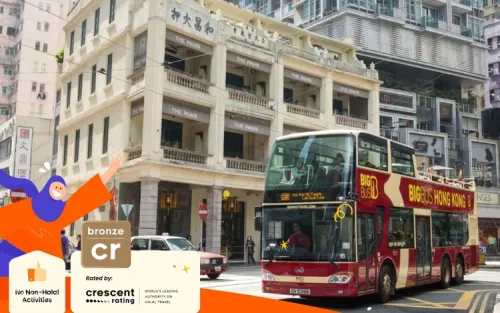 Open-top double-decker bus driving through the vibrant streets of Kowloon