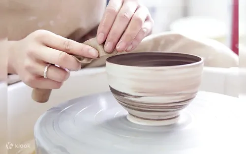 Hands shaping clay on a spinning pottery wheel