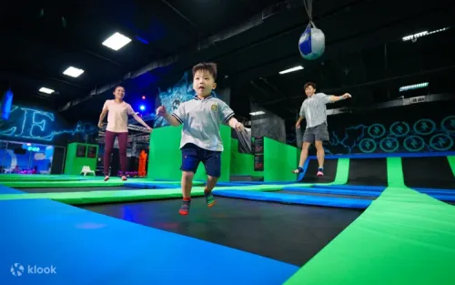 Excited visitors jumping high on interconnected indoor trampolines