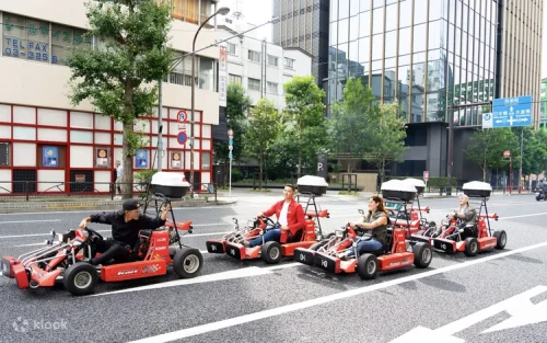 A convoy of go-karts driving past the bright neon signs and electronics stores of Akihabara