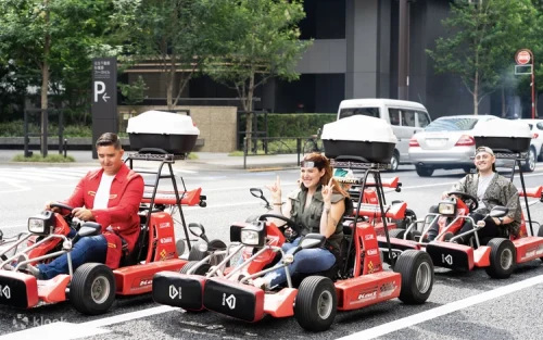 Driver behind the wheel of a custom street go-kart smiling for the camera in downtown Tokyo