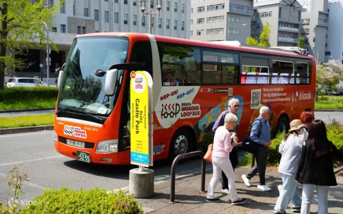 Passengers enjoying the refreshing breeze on the open-top sightseeing bus in Osaka.