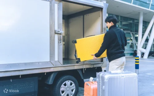 Professional courier loading luggage into a secure transport van in Seoul