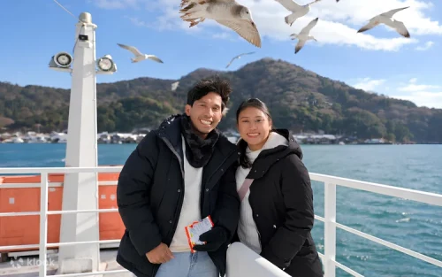 Joyful visitors feeding seagulls from a sightseeing boat in the beautiful Ine Bay.
