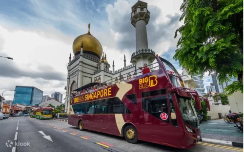 Double-decker sightseeing bus cruising past the iconic Marina Bay Sands