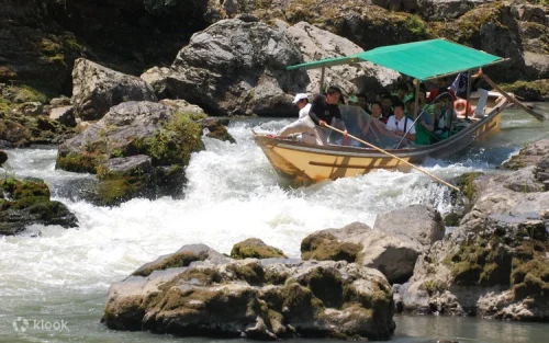 Passengers enjoying a serene river cruise surrounded by Kyoto mountains