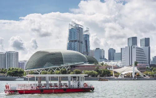 Traditional wooden bumboat sailing past the iconic Merlion statue in Singapore